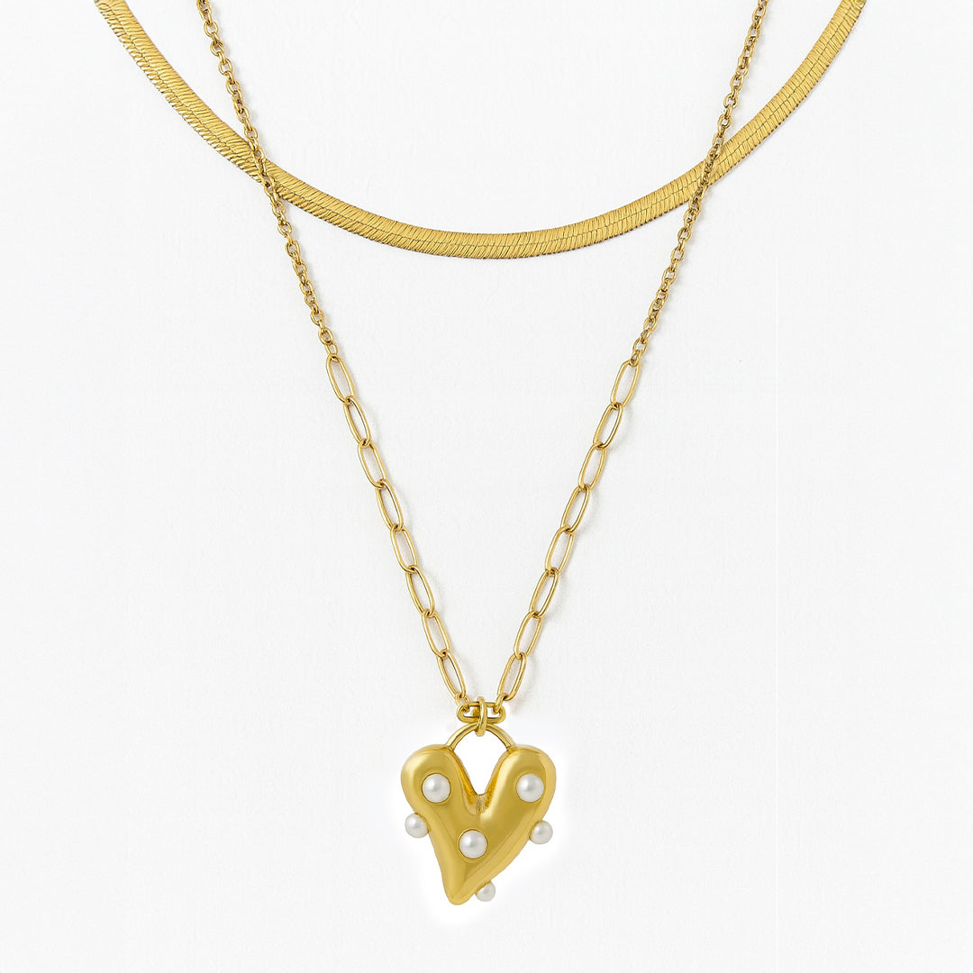 Gold necklace with a heart-shaped pendant on a white background
