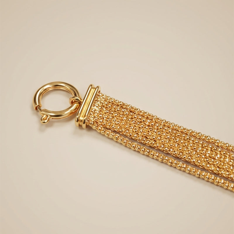 Gold chain bracelet on a beige background