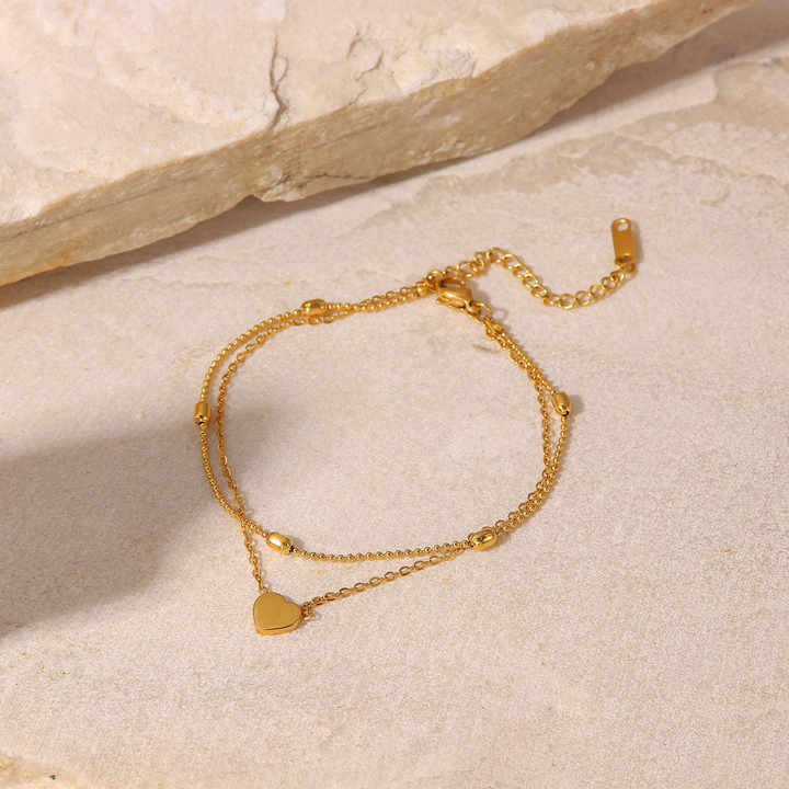 Gold Anklet with heart charm on a light stone surface