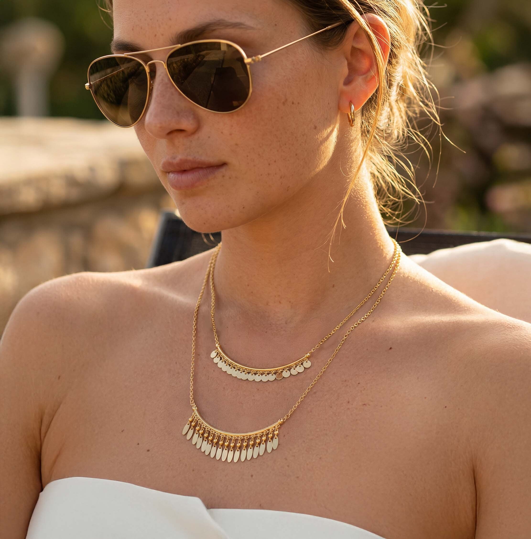Woman wearing a layered gold necklace for women featuring delicate coin charms and dangling fringe details