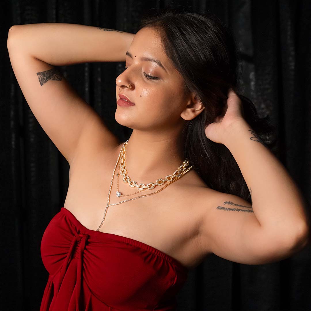 Woman in a red dress with gold necklaces for women against a black background