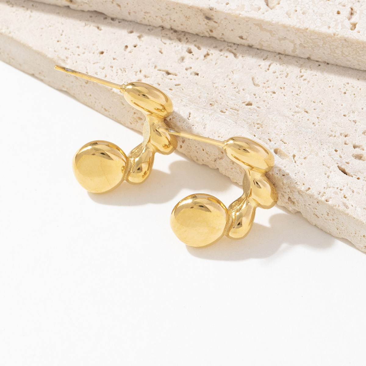 Gold earrings  for women on a textured stone surface