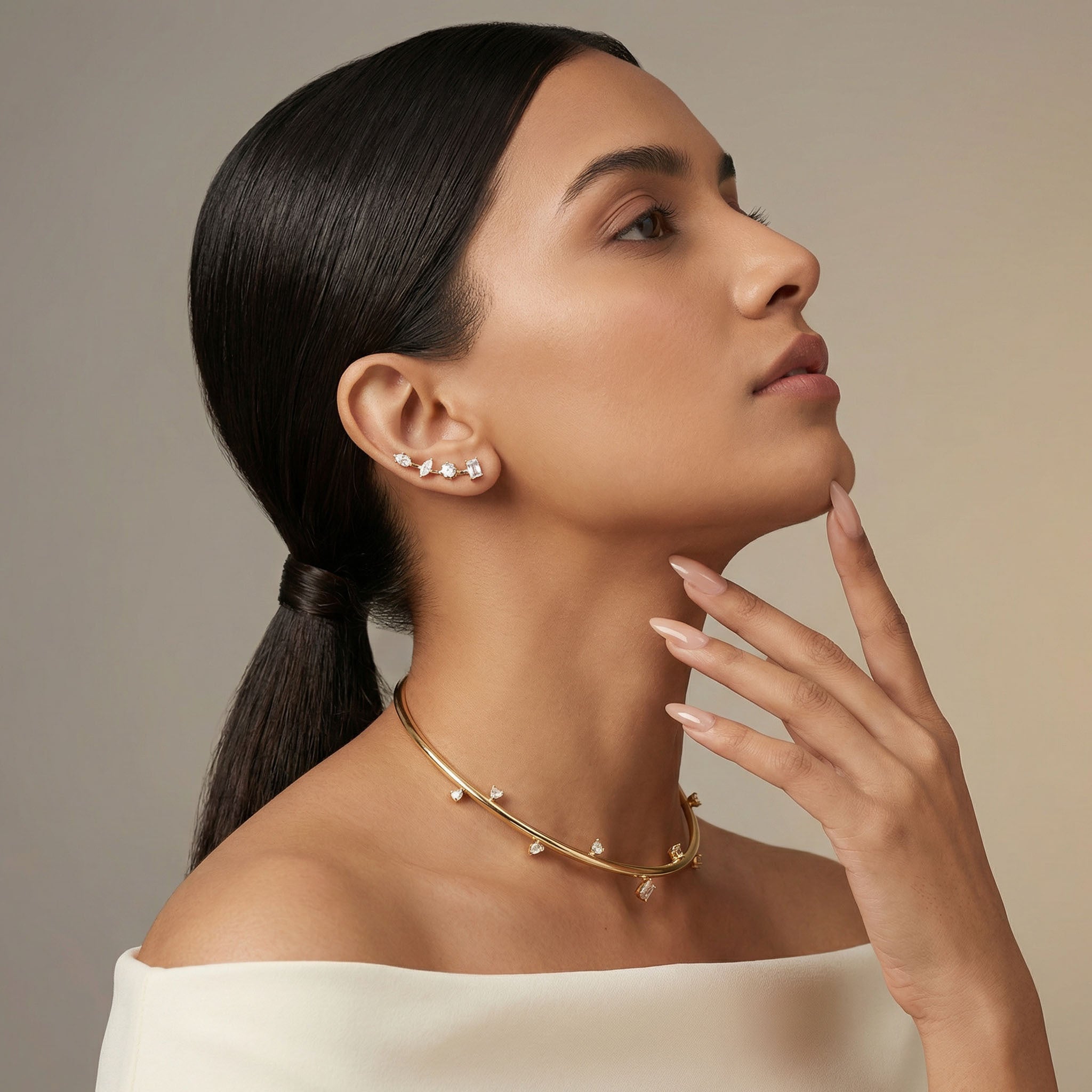 Woman wearing a gold necklace and earrings against a neutral background