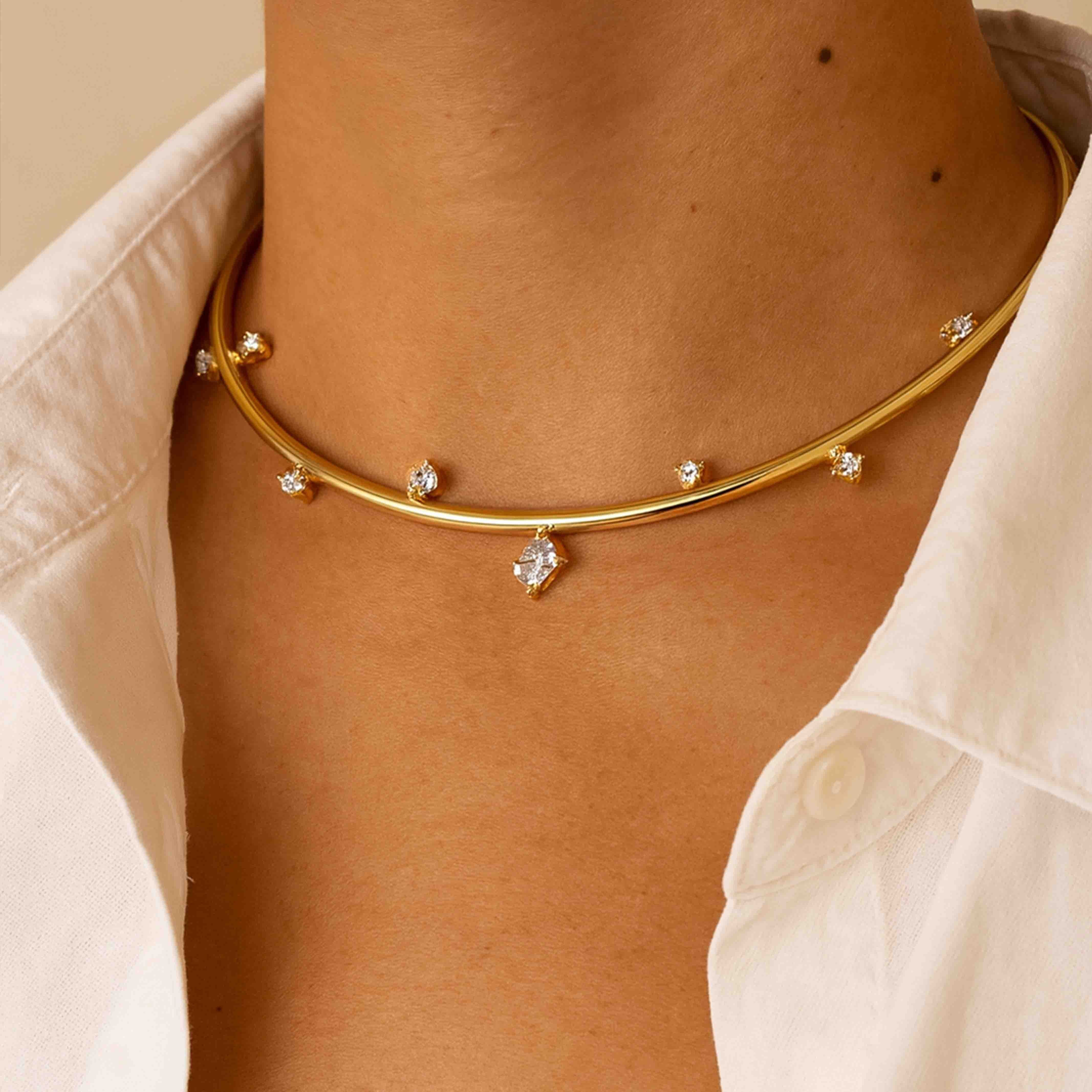 Gold necklace with small diamonds on a person wearing a light-colored shirt.