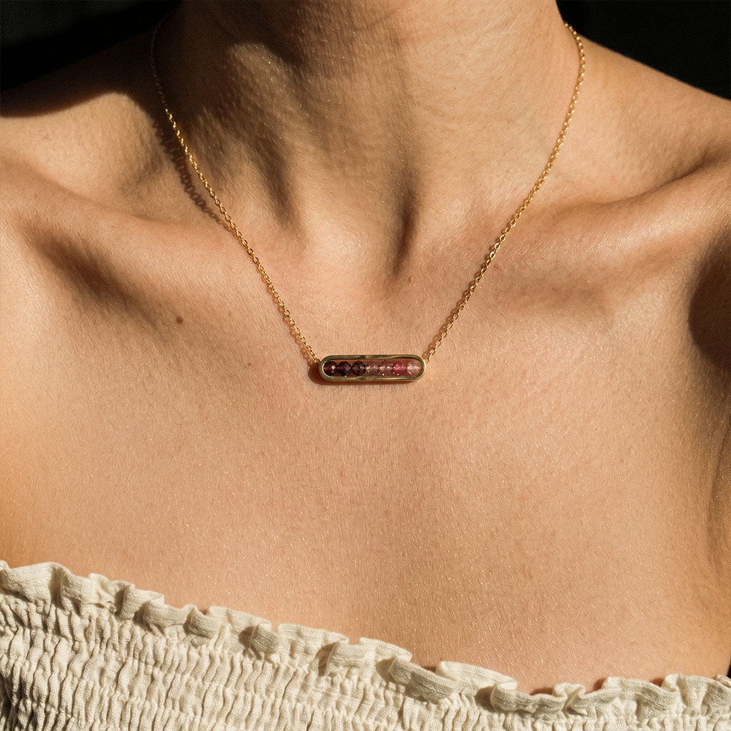 Necklace with a pendant on a person's neck against a neutral background