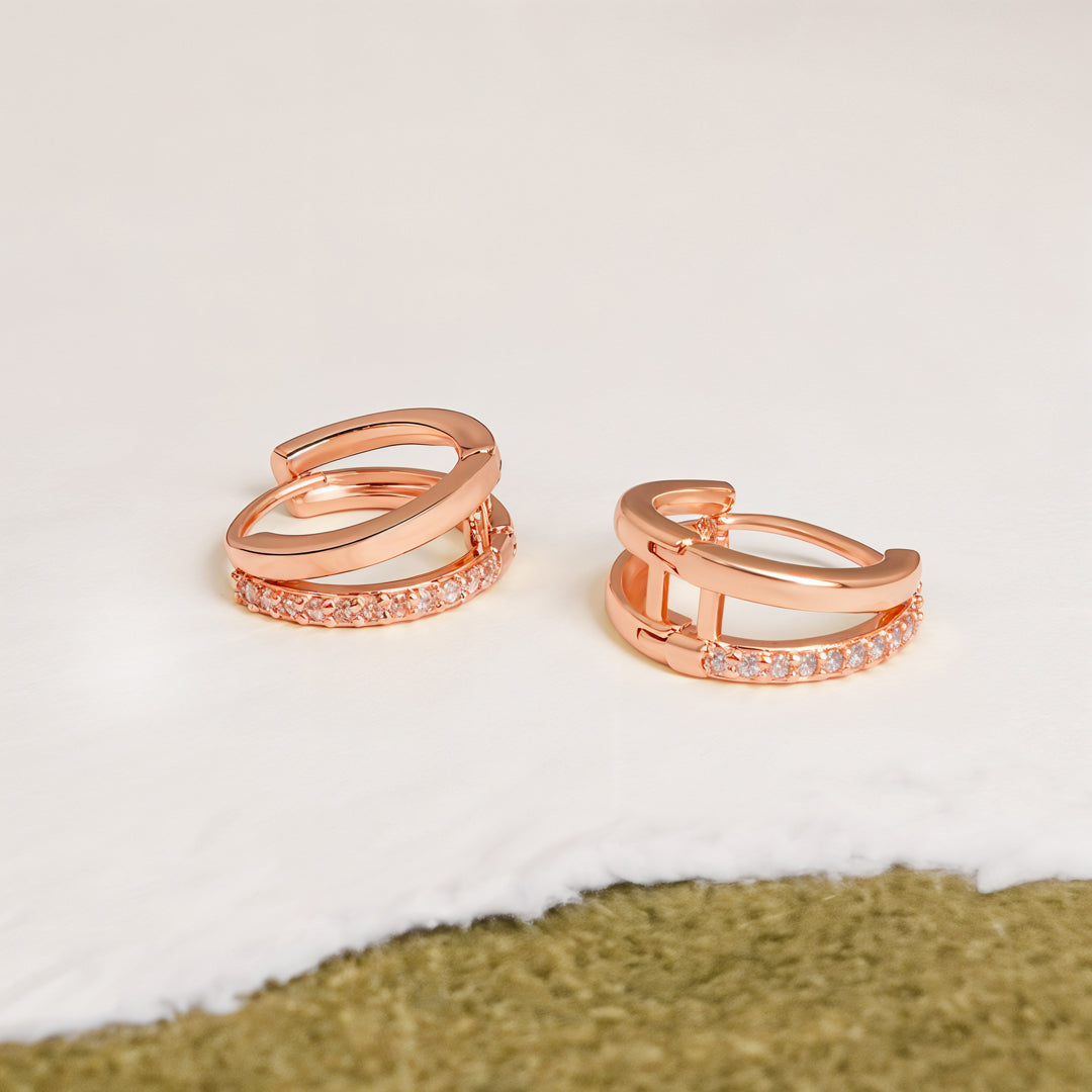 Rose gold hoop earrings with embedded stones on a light background