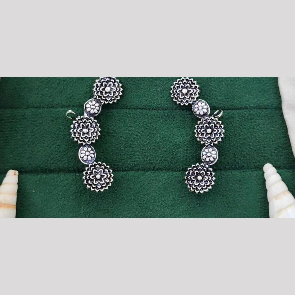 Pair of silver floral earrings on a green jewelry box