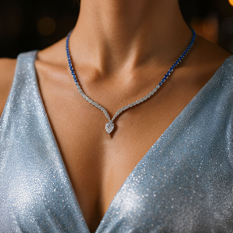 Close-up of a woman wearing a blue beaded necklace and a sparkly silver top.
