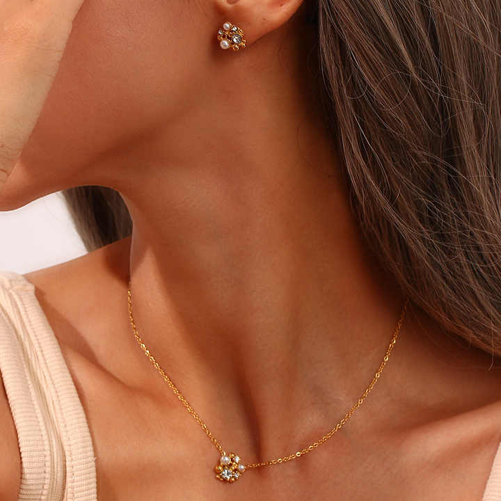 Close-up of a woman wearing a gold necklace and matching earrings.