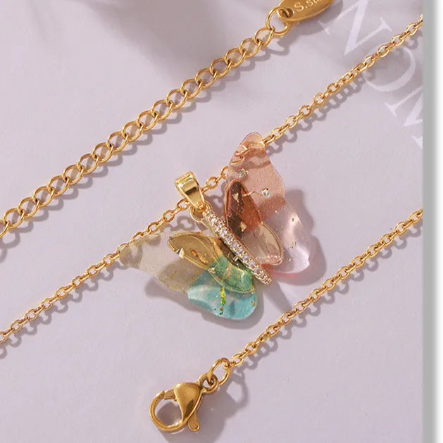 Gold chain necklace with colorful pendant on a light gray 