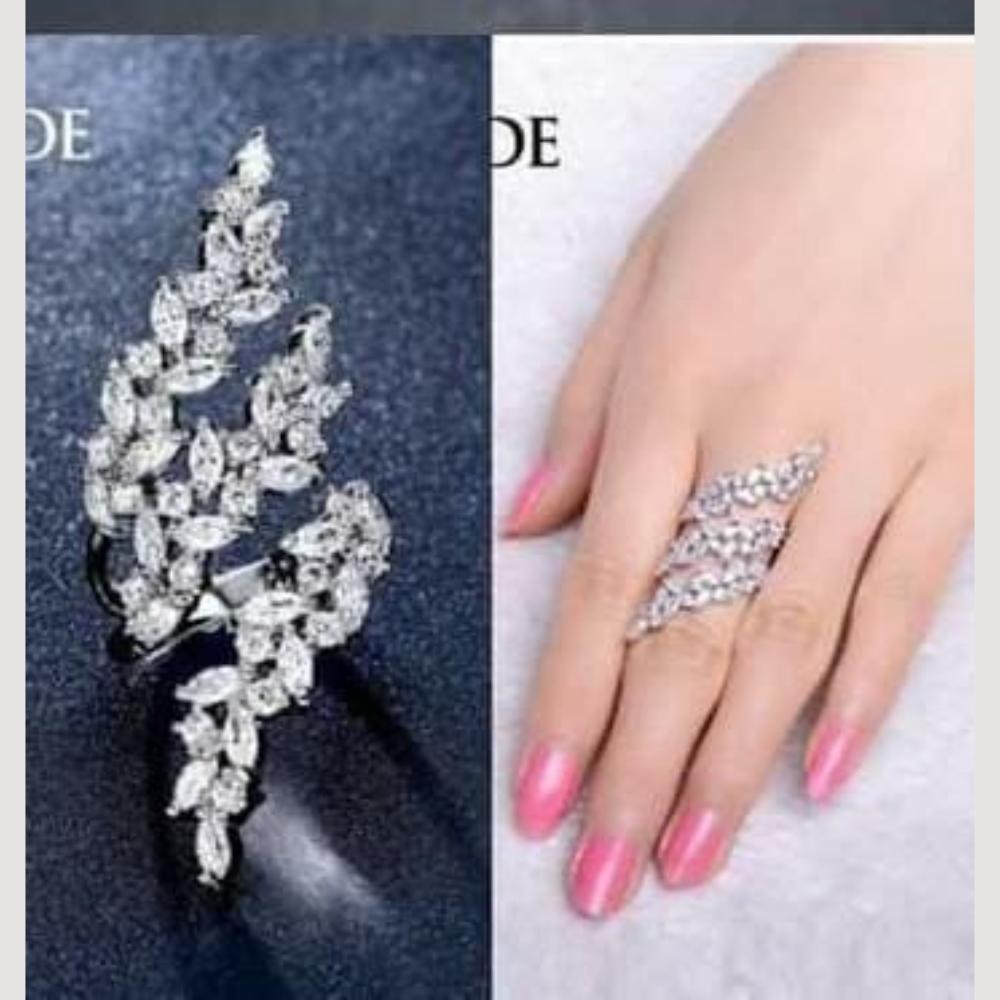 Silver leaf-shaped earring and ring on a hand with pink nails.