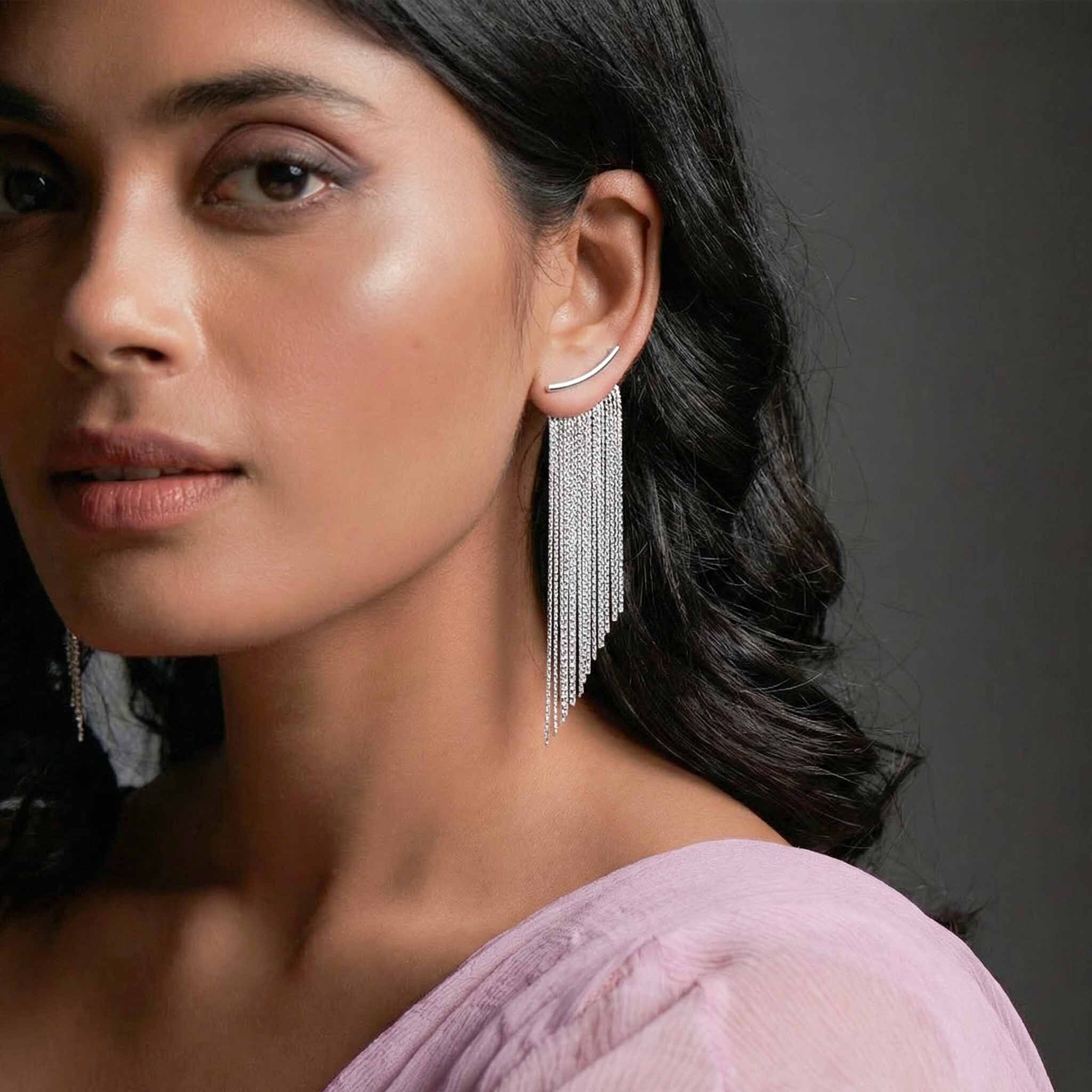 Woman wearing silver tassel earrings  for women against a dark background