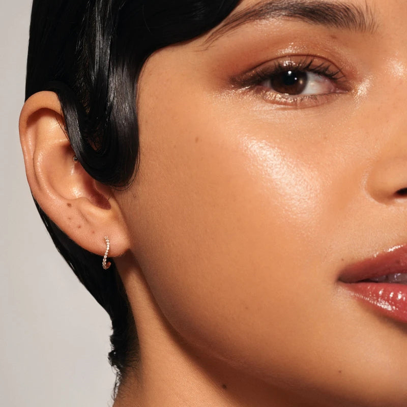 Close-up of a person wearing an earring with a neutral background
