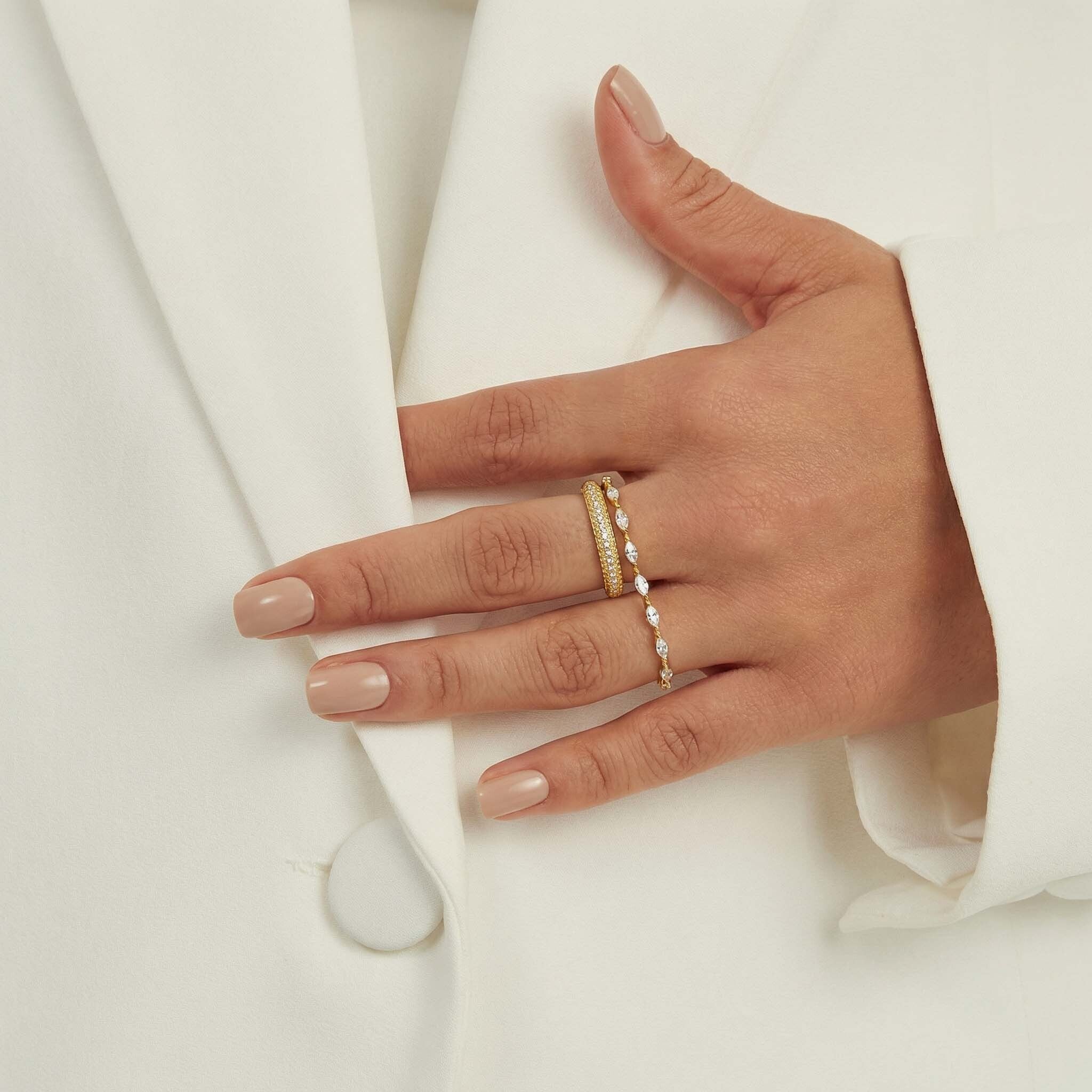 Hand wearing a gold ring with pearls on a white background