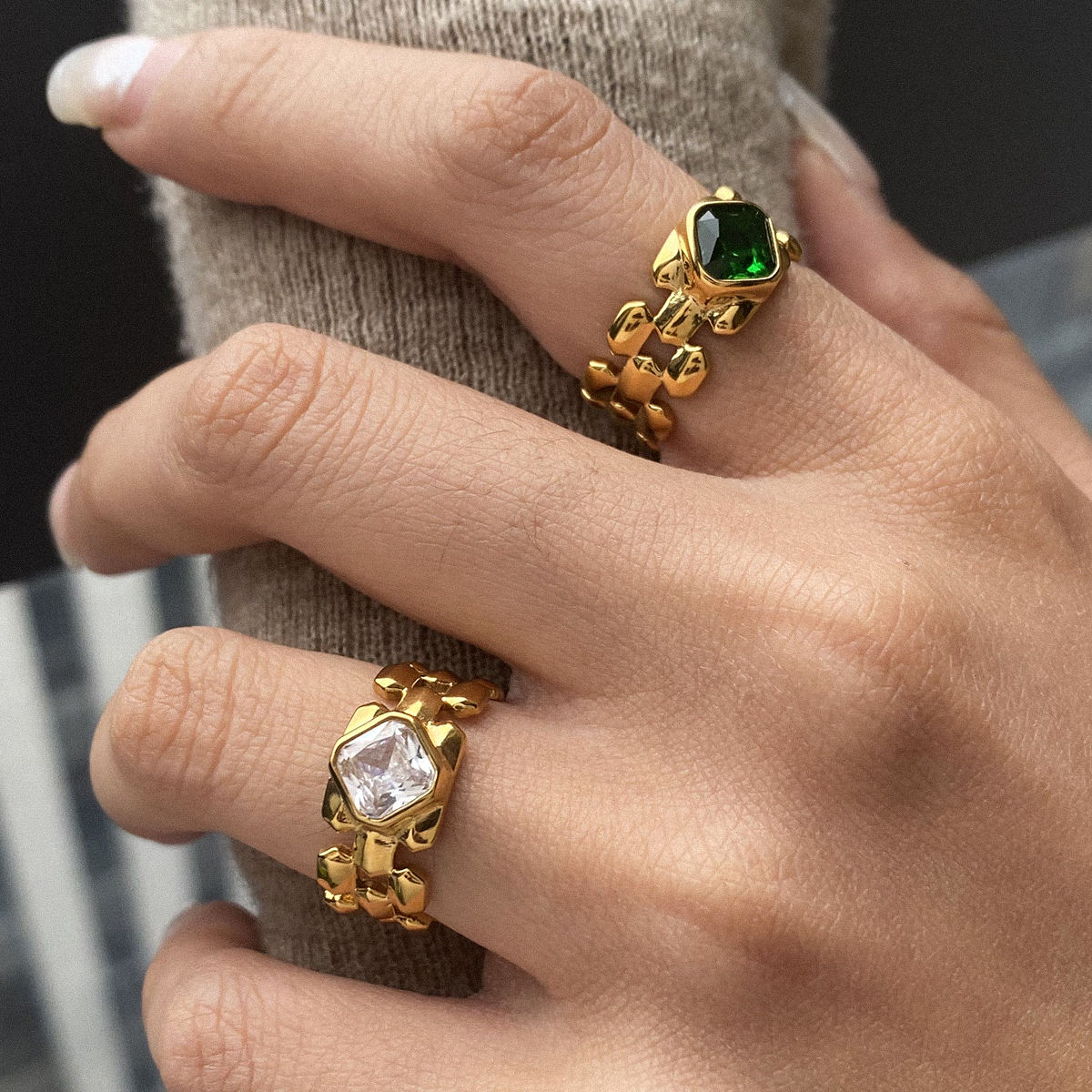 Close-up of a hand wearing two gold rings with gemstones.