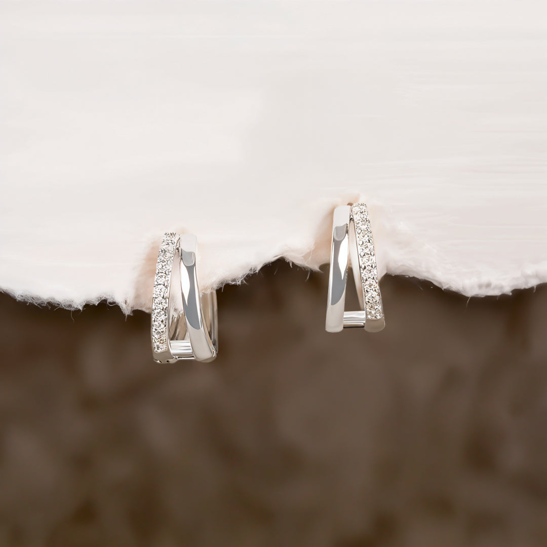 Pair of silver hoop earrings on a textured surface with a blurred background