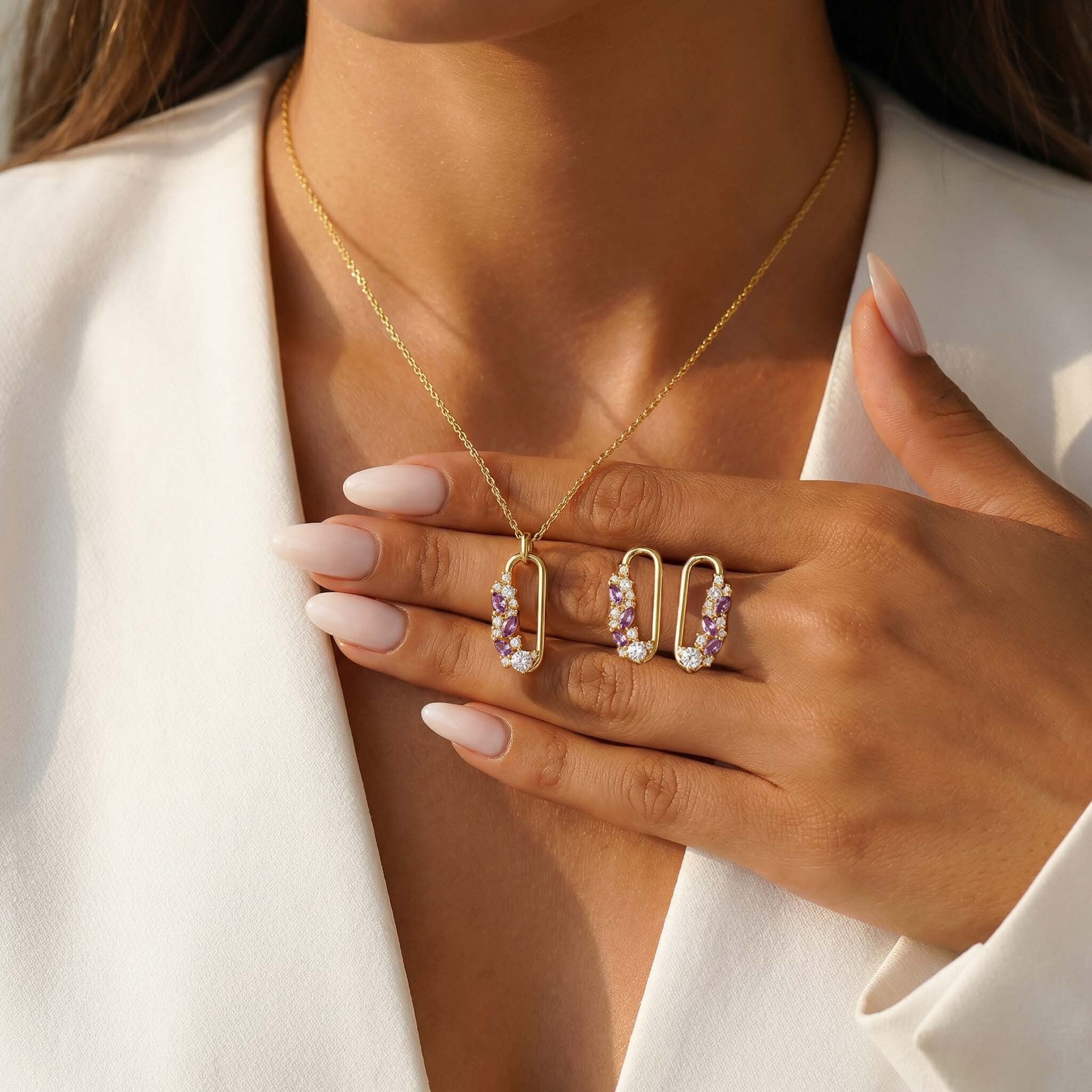 Jewelry set including a necklace, earrings, and ring on a person wearing a white blazer.
