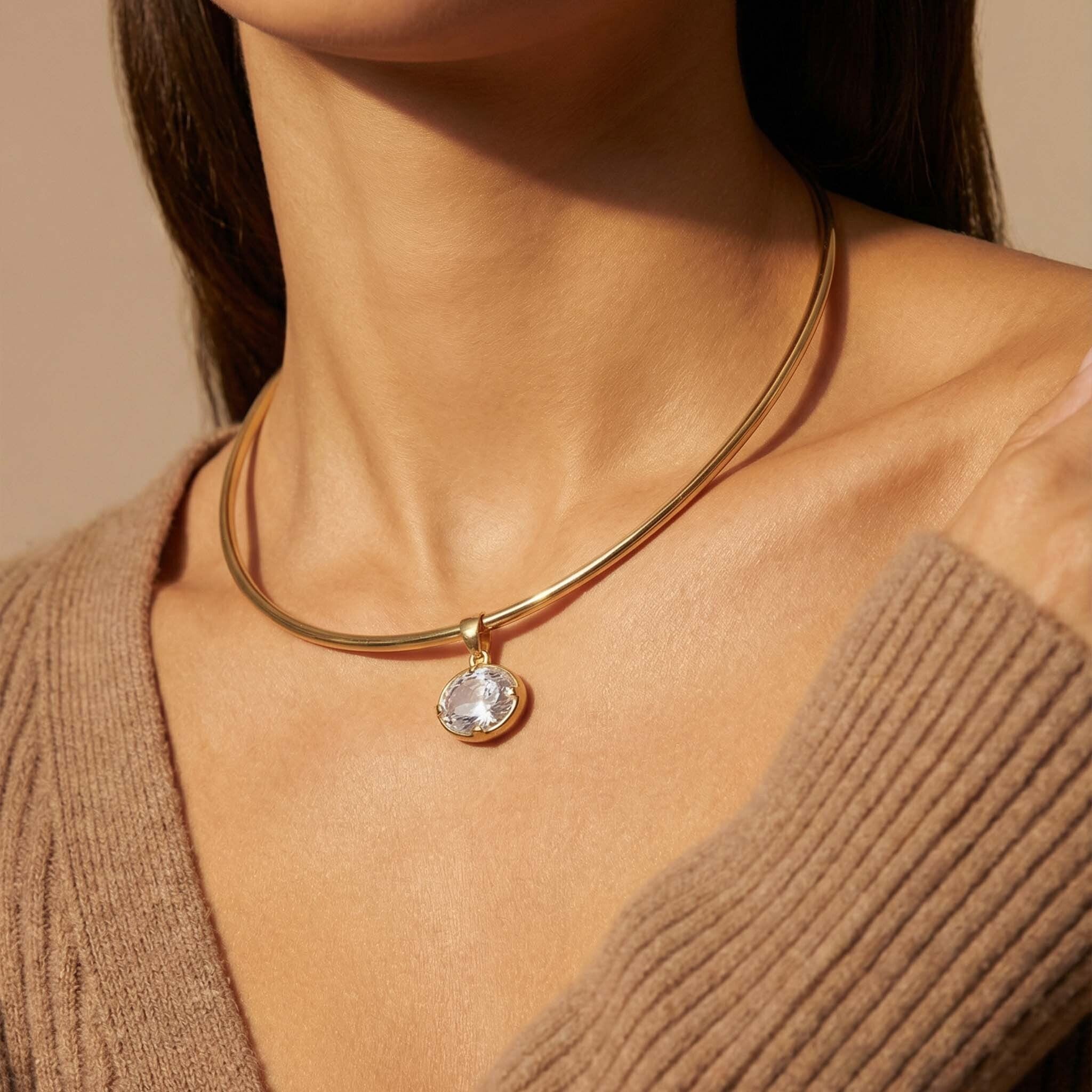 Gold necklace for women  with a pendant worn by a person against a neutral background