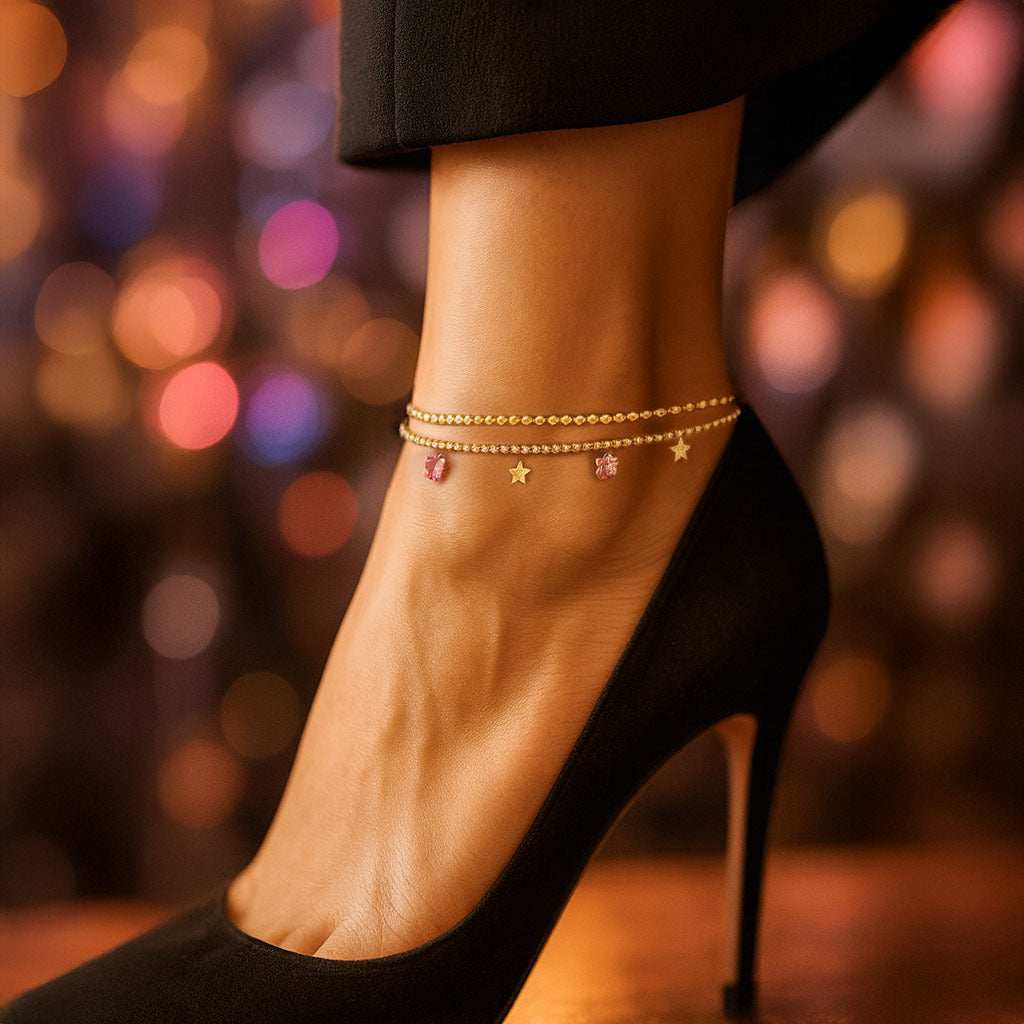 Ankle with gold anklets and black high-heeled shoes against a blurred colorful background