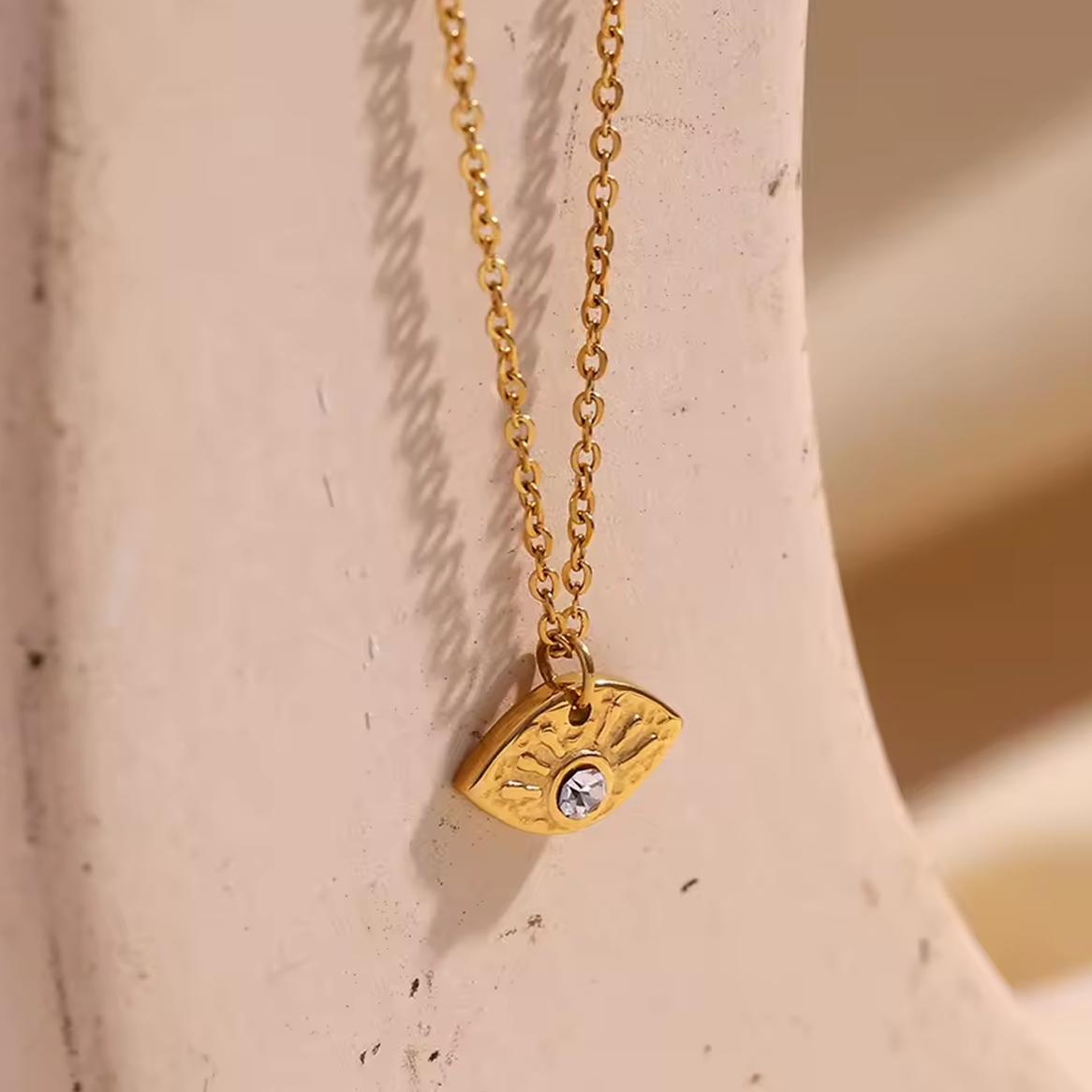 Gold necklace with a pendant on a beige surface