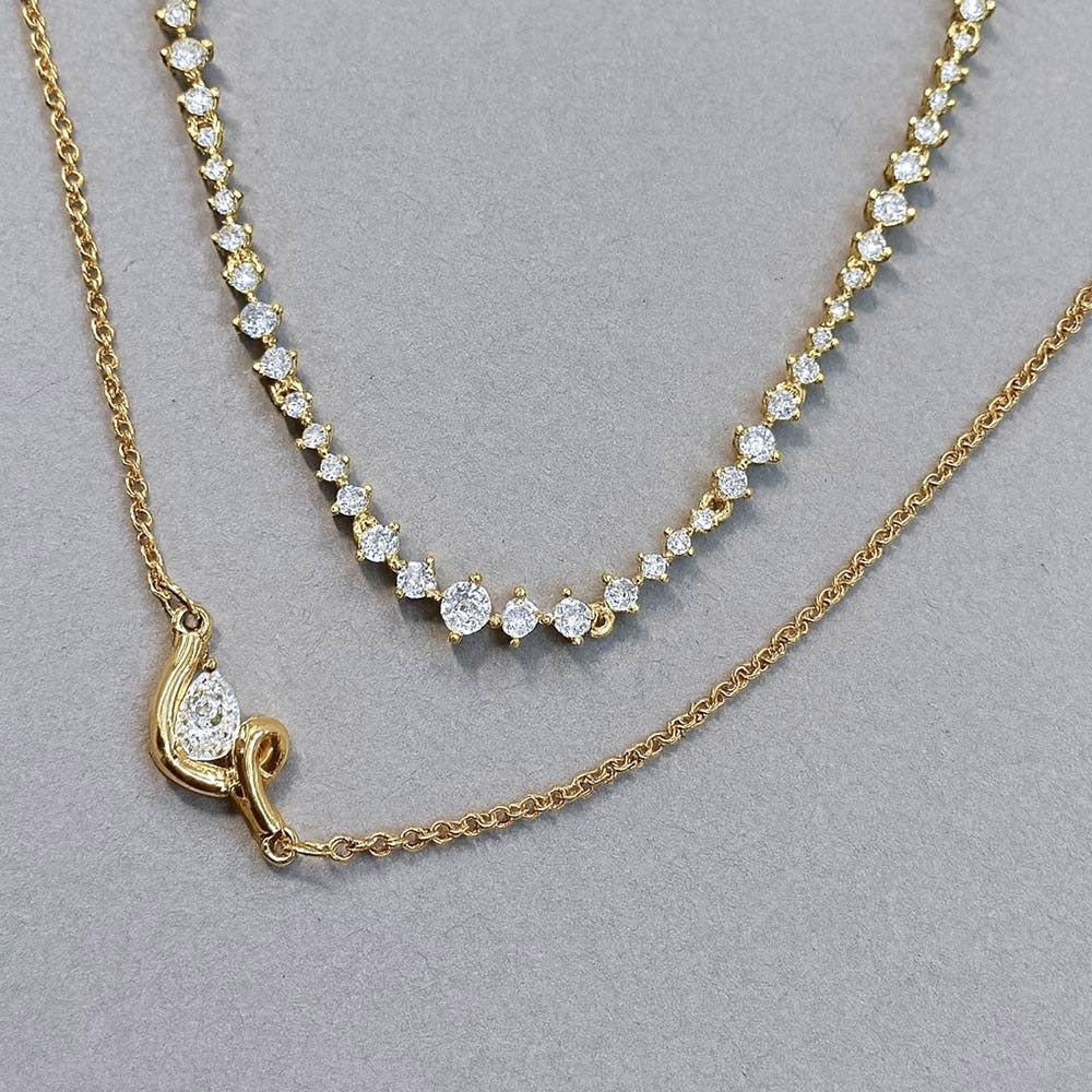 Two-layer gold necklaces for women featuring a pear-shaped pendant on a fine chain paired with a delicate row of white stones, styled on a model wearing a black V-neck top.