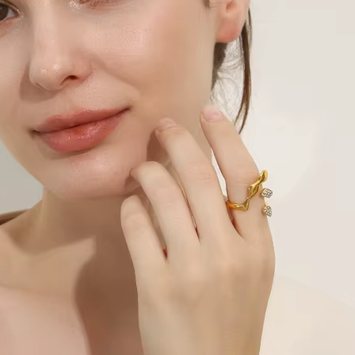 Close-up of a woman's hand with gold rings on a neutral background