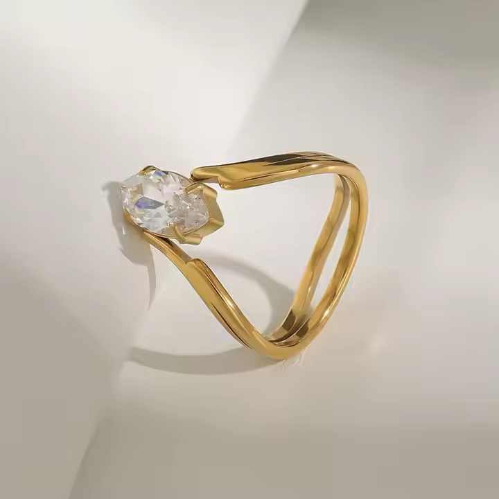Gold ring with a clear gemstone on a light gray background