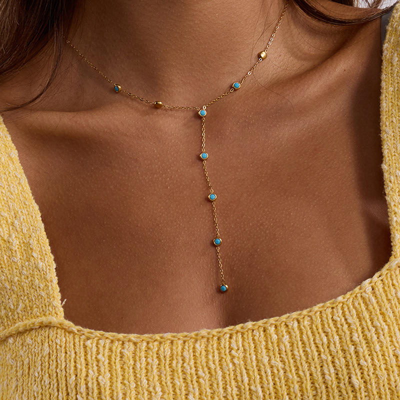 Necklace with turquoise stones worn by a person in a yellow top