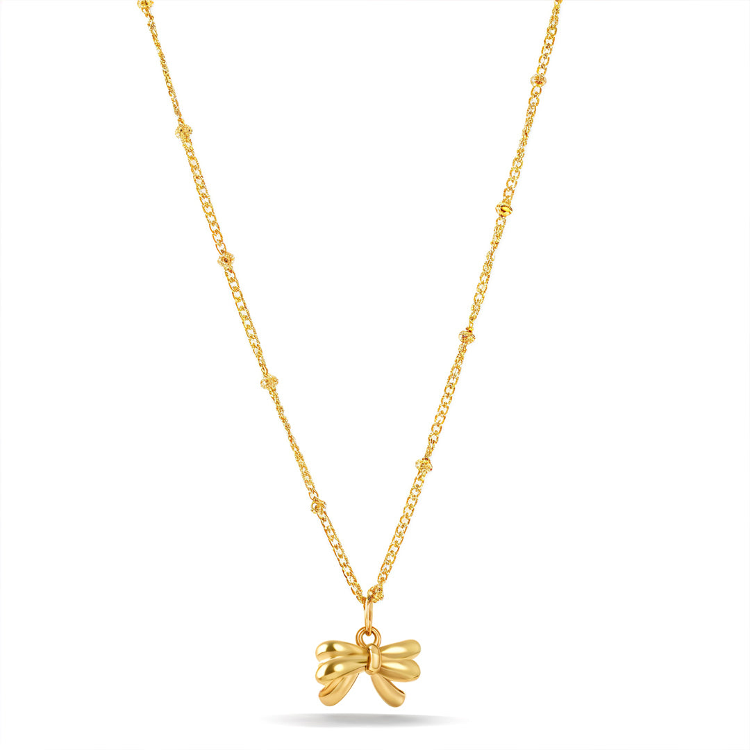 Gold necklace with a bow pendant on a white background