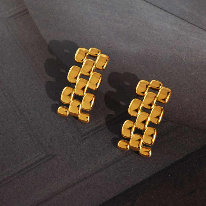 Gold chain-link earrings for women on a dark background