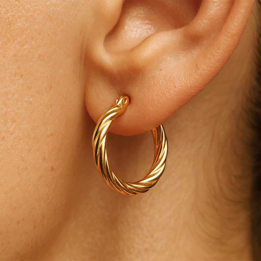 Gold hoop earrings for women worn on a person's ear with a close-up view.