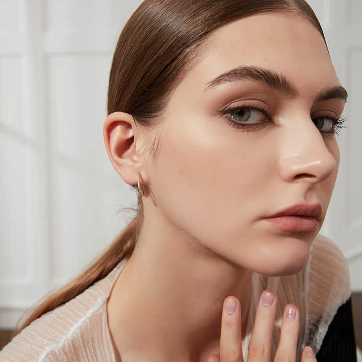 Close-up of a earrings for woman with a neutral expression, wearing a light-colored top.