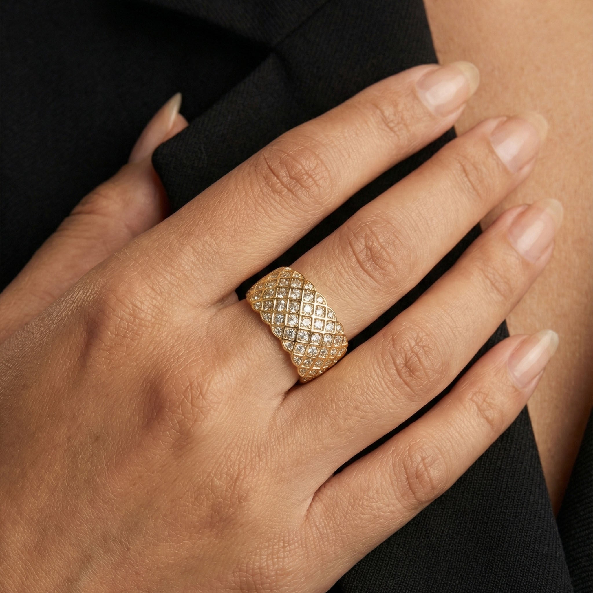 Gold ring with diamond accents on a hand against a black background