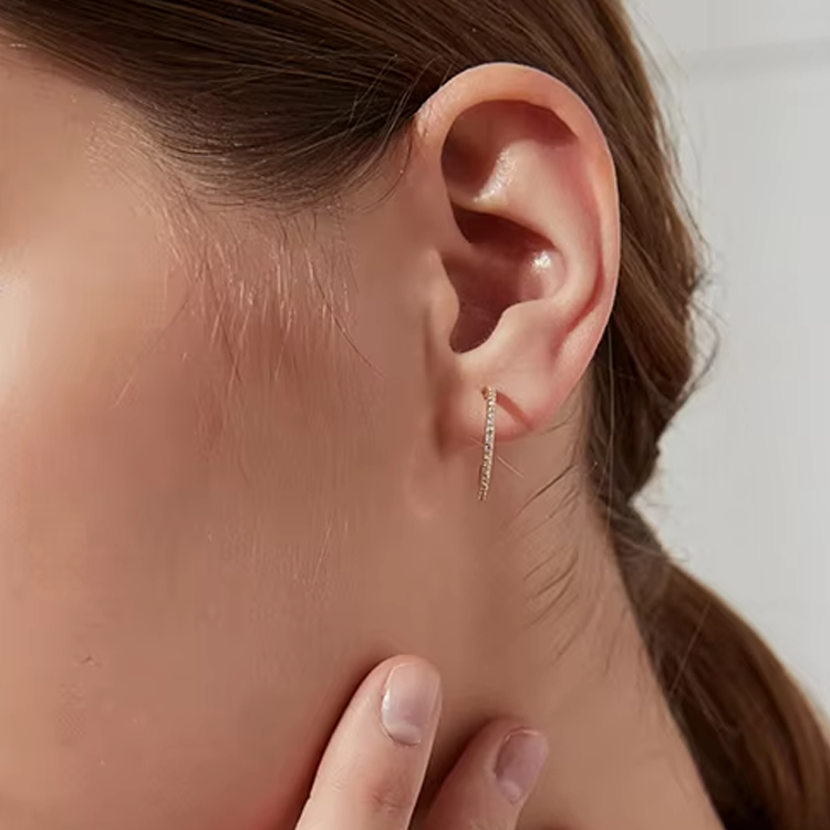 Close-up of an ear wearing a gold hoop earrings for women with a blurred background