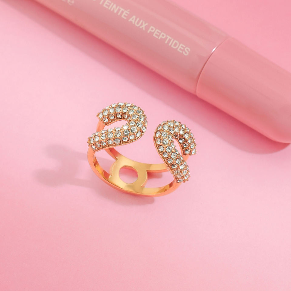 Gold ring with gemstones on a pink background