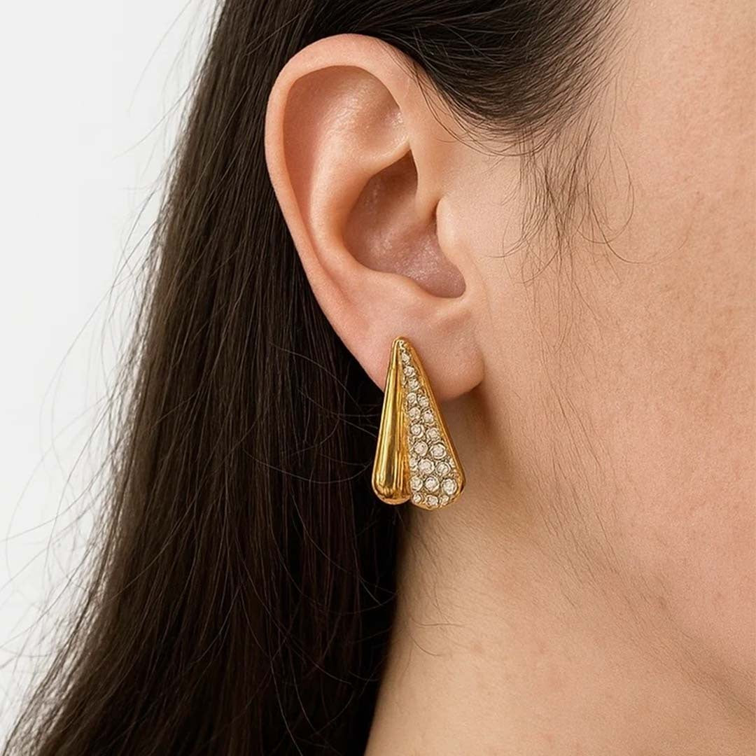 Gold earring with clear stones worn by a person with dark hair.