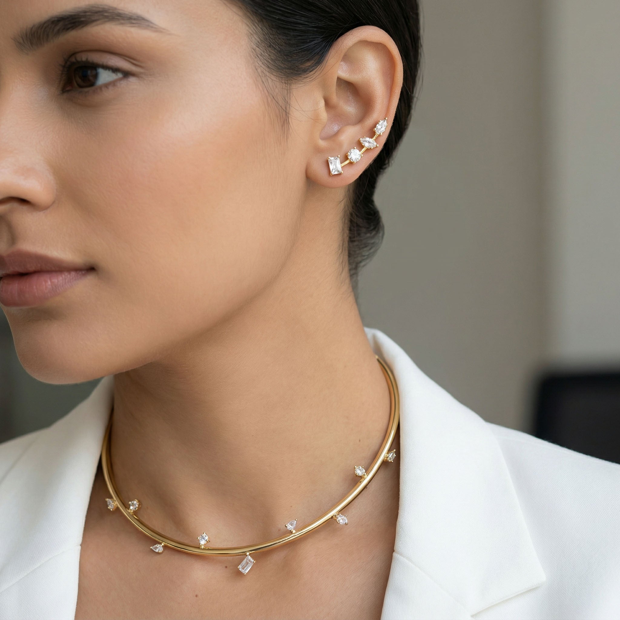 Close-up of a woman wearing gold necklace and diamond earrings.