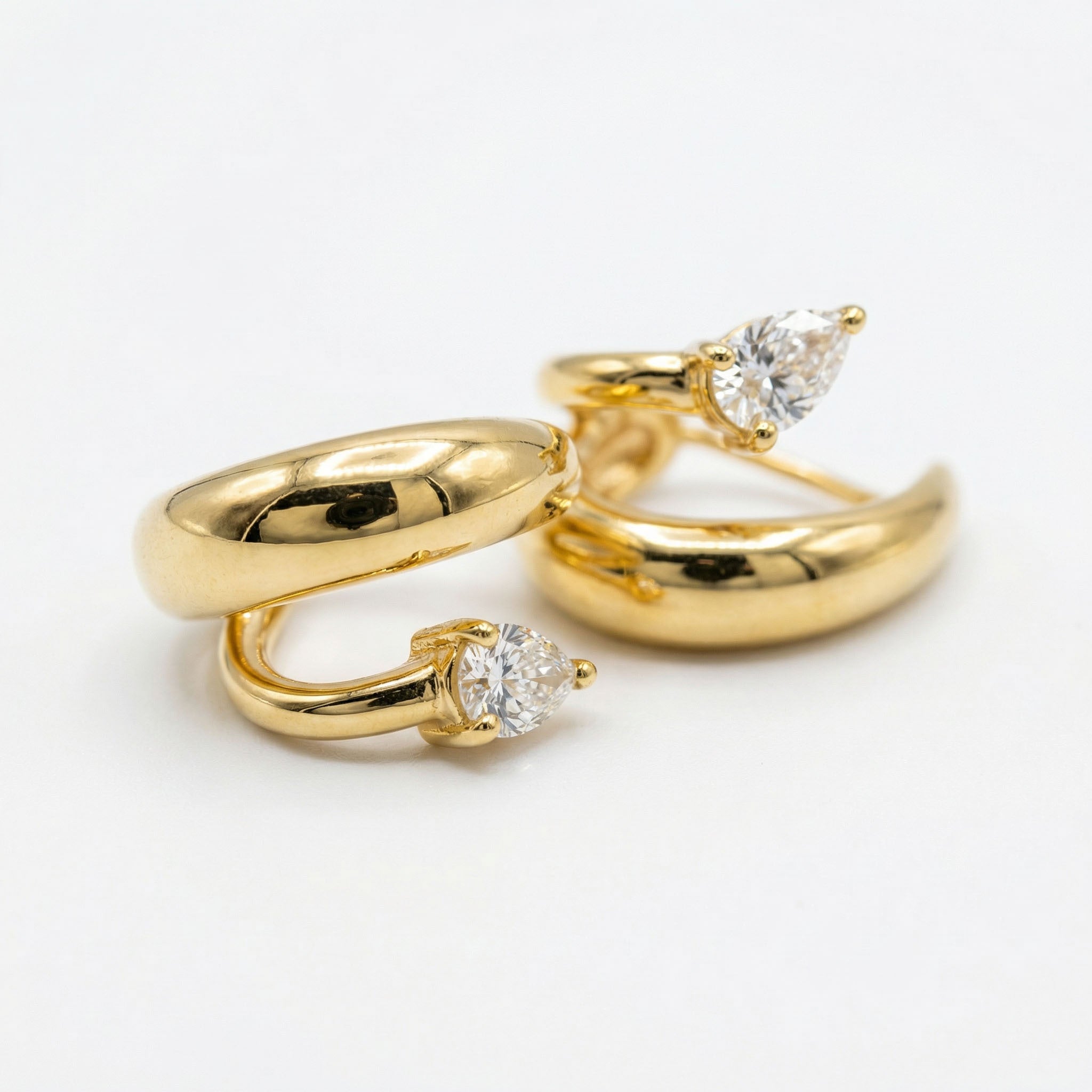 Two gold hoop earrings with diamond accents on a white background