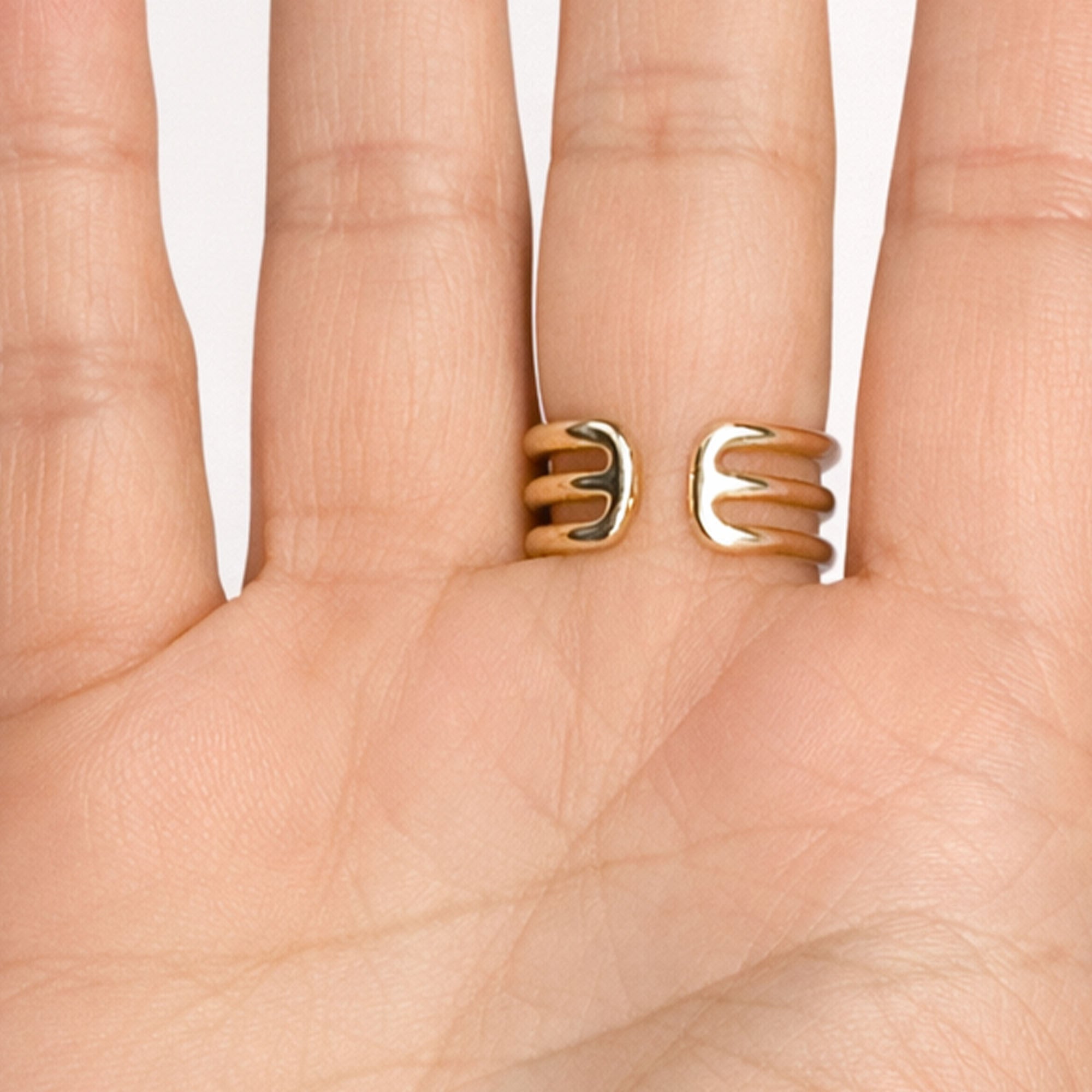 Gold spiral ring on a hand against a white background