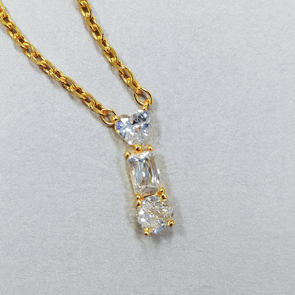 Gold necklace with a diamond pendant on a light gray background