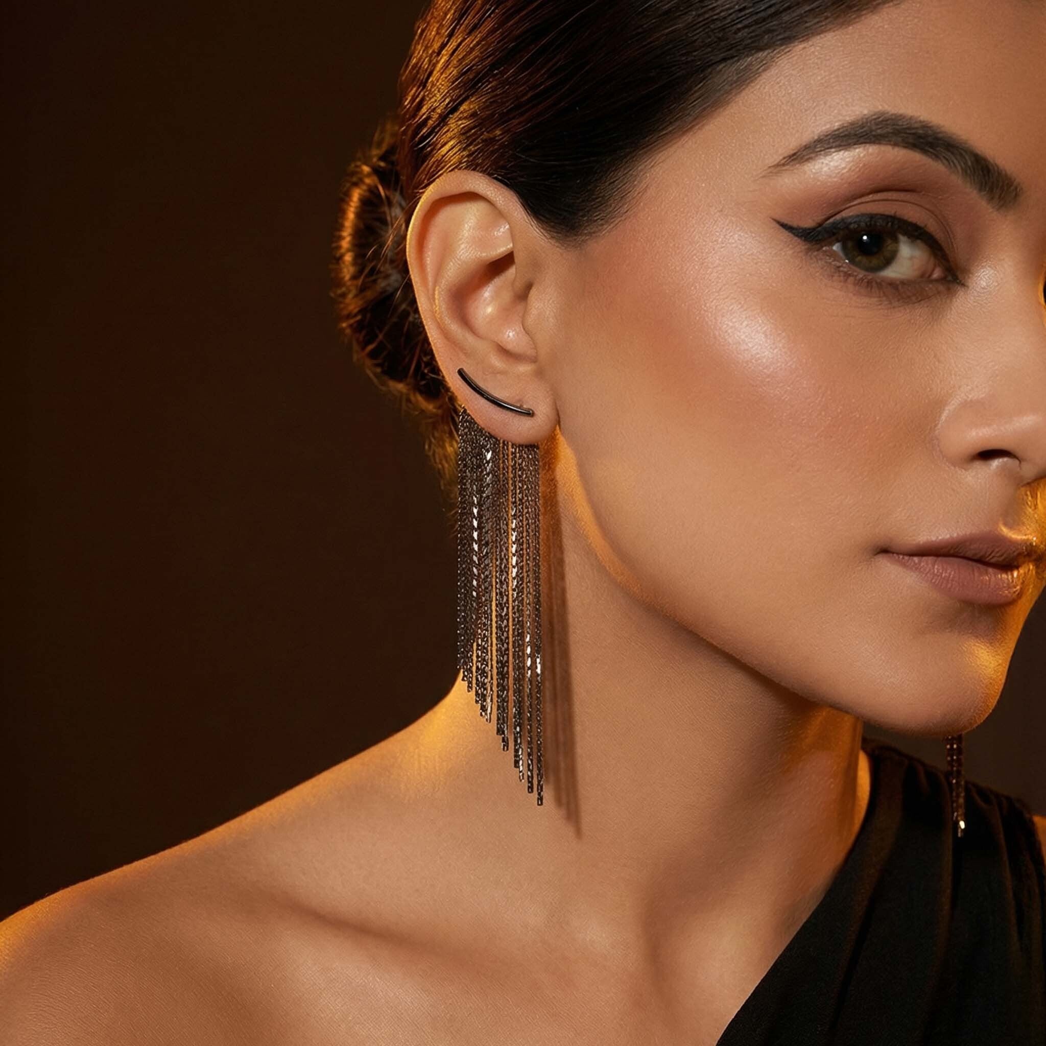 Close-up of a woman wearing long, dangling earrings for women with a dark background