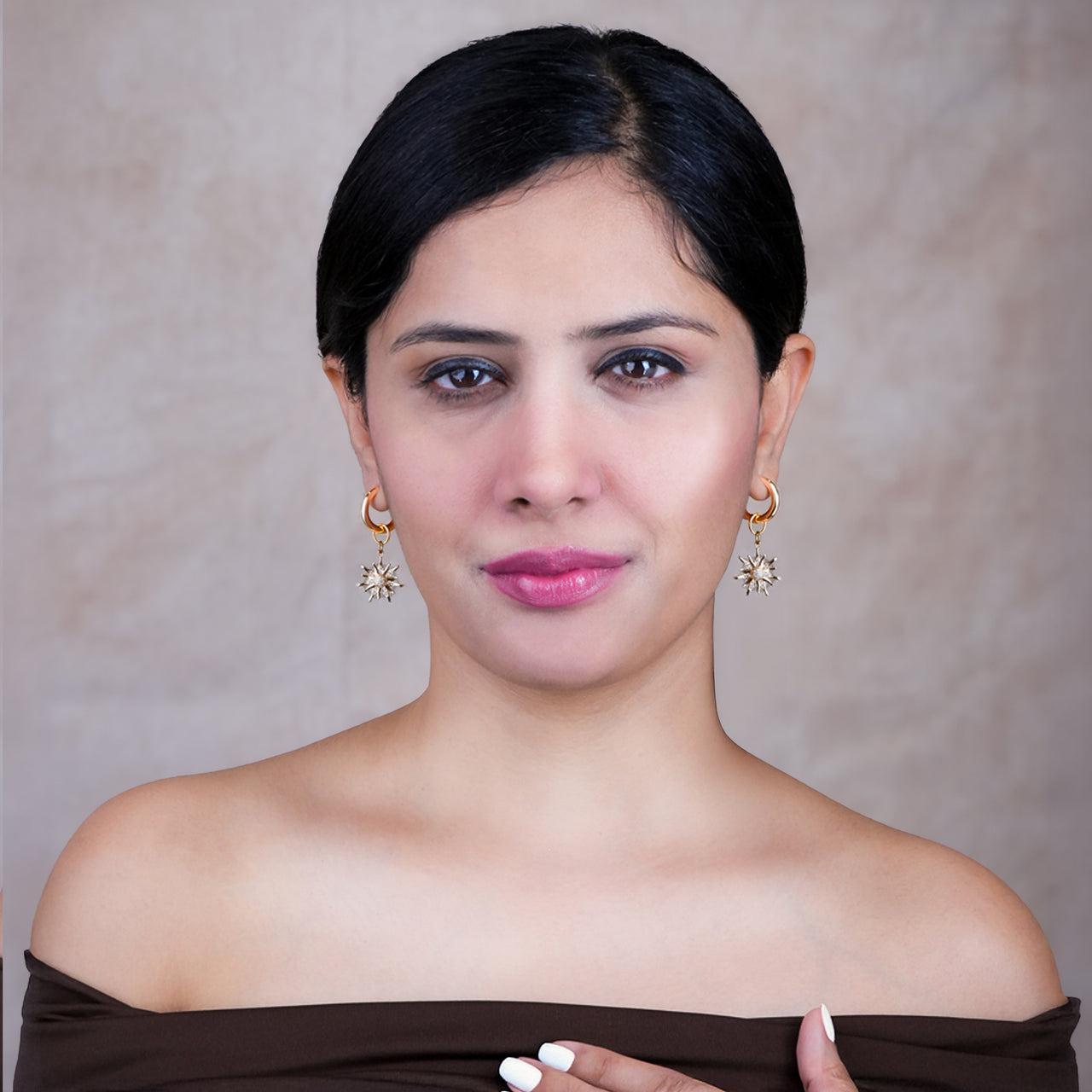 Woman wearing gold earrings for women with a neutral background
