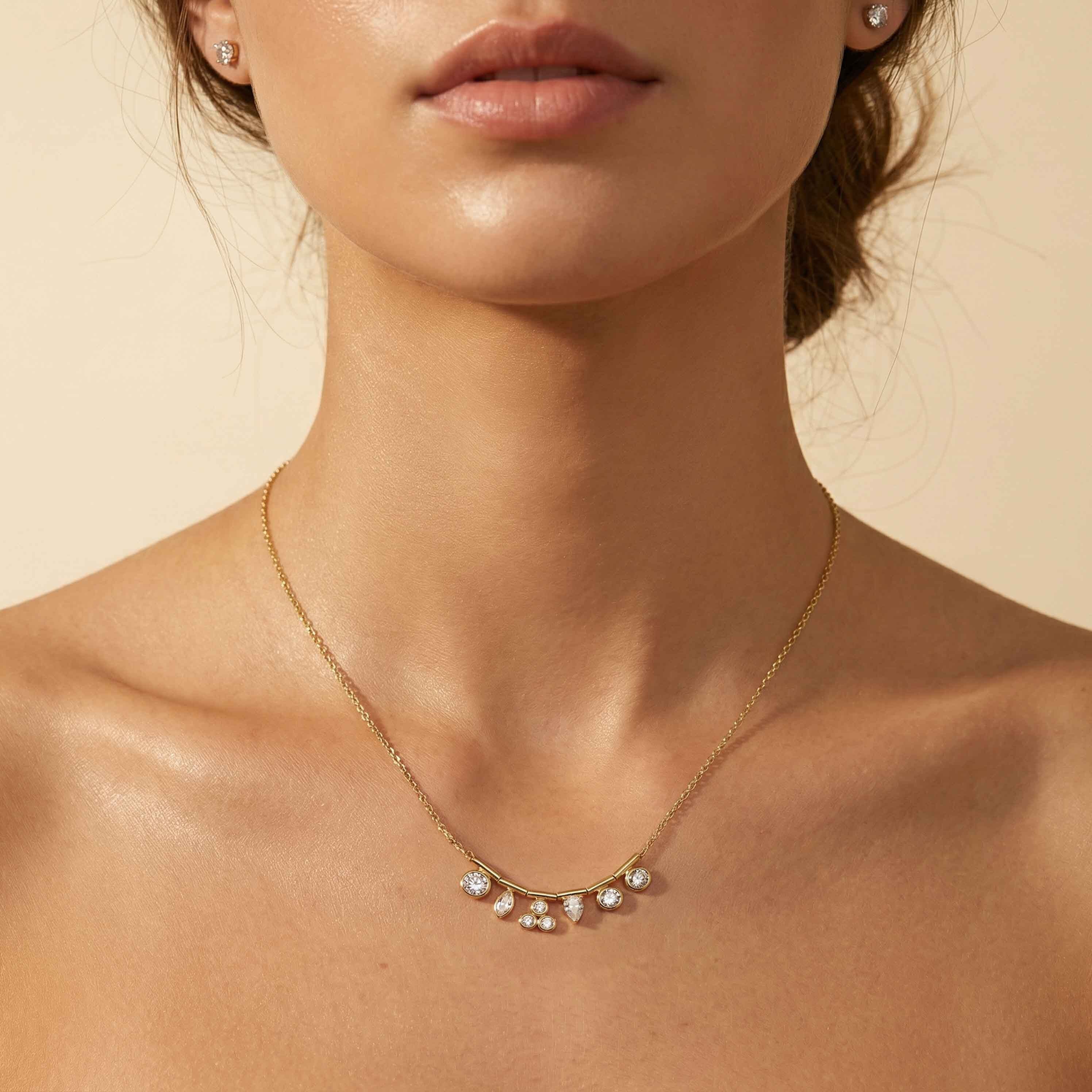 Close-up of a woman wearing a gold necklace with pearl-like stones on a beige background