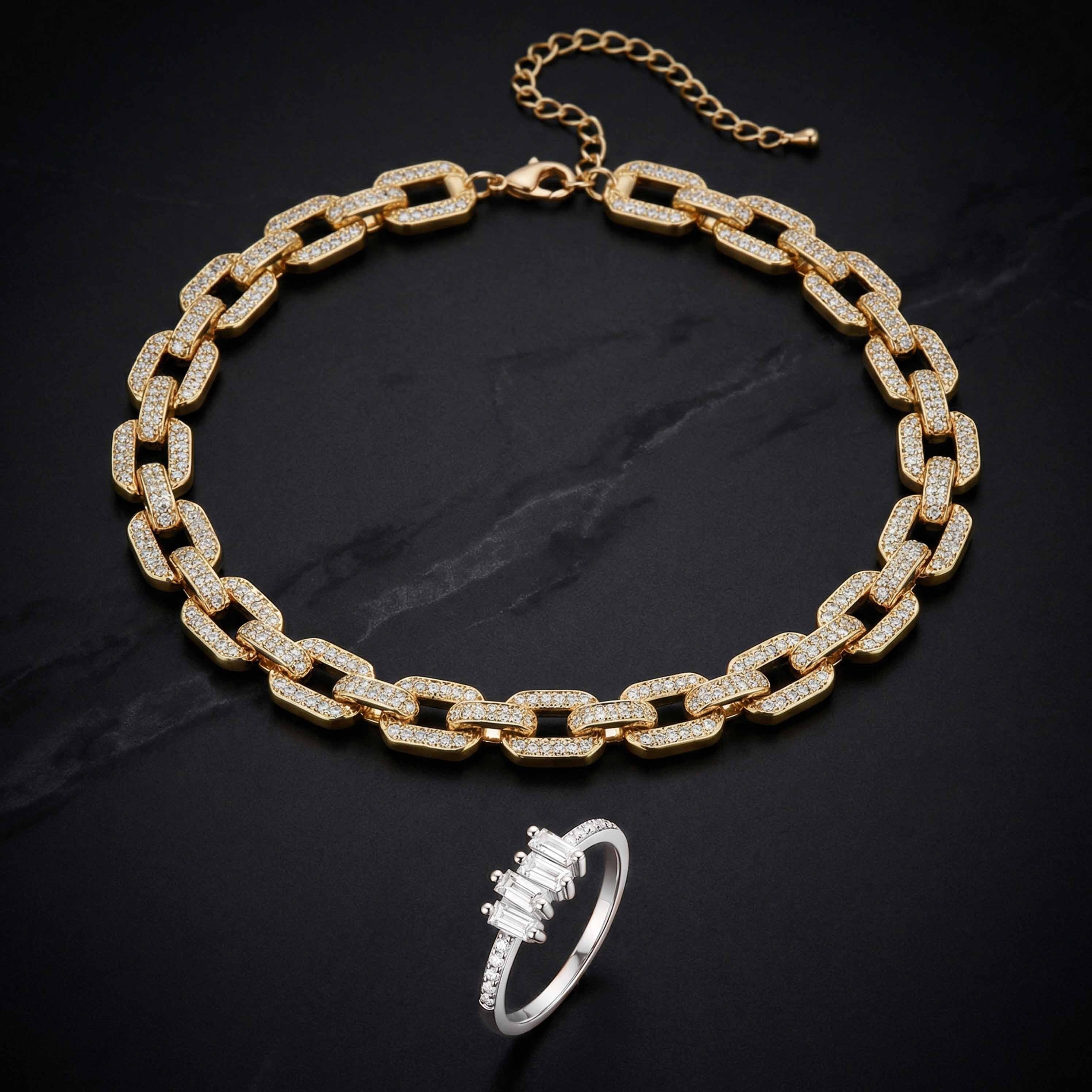 Gold chain necklace and silver ring on a dark surface