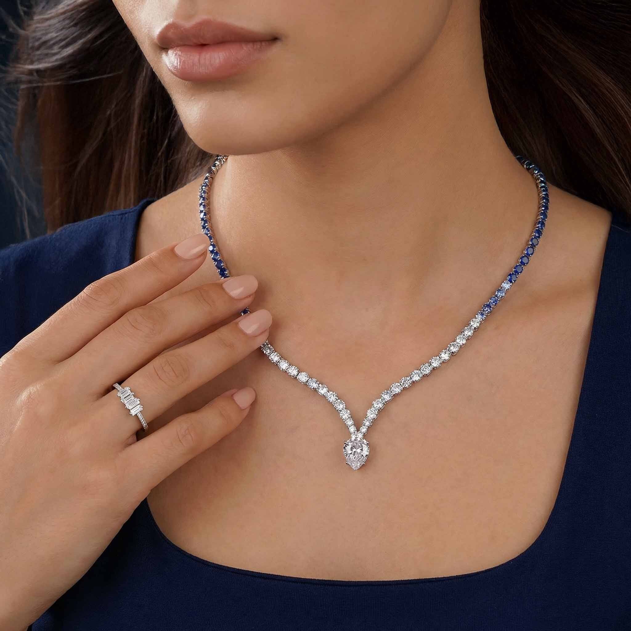 Woman wearing a diamond necklace with a close-up of the necklace and ring on her finger.
