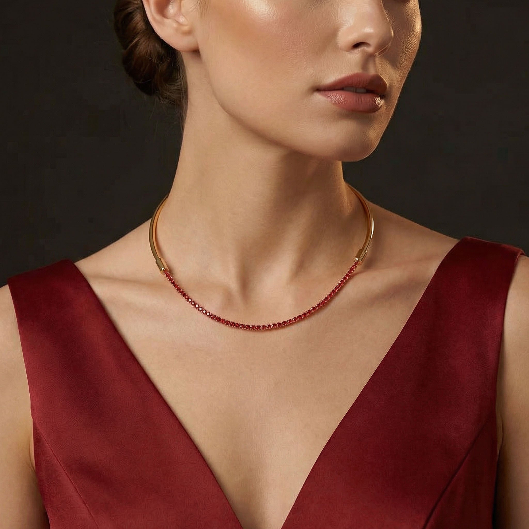 Woman wearing a red dress and gold necklace against a dark background