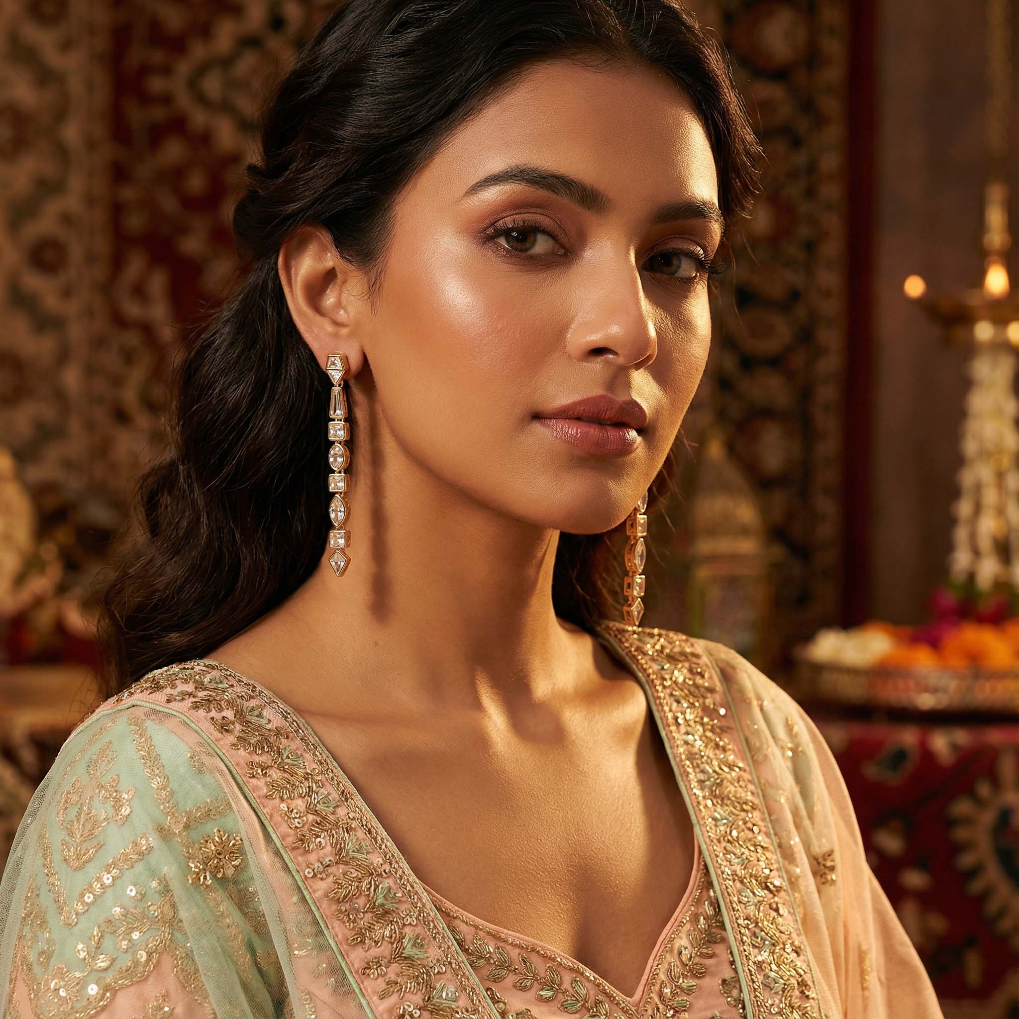 Woman wearing traditional embroidered attire with jewelry in a warm-toned setting